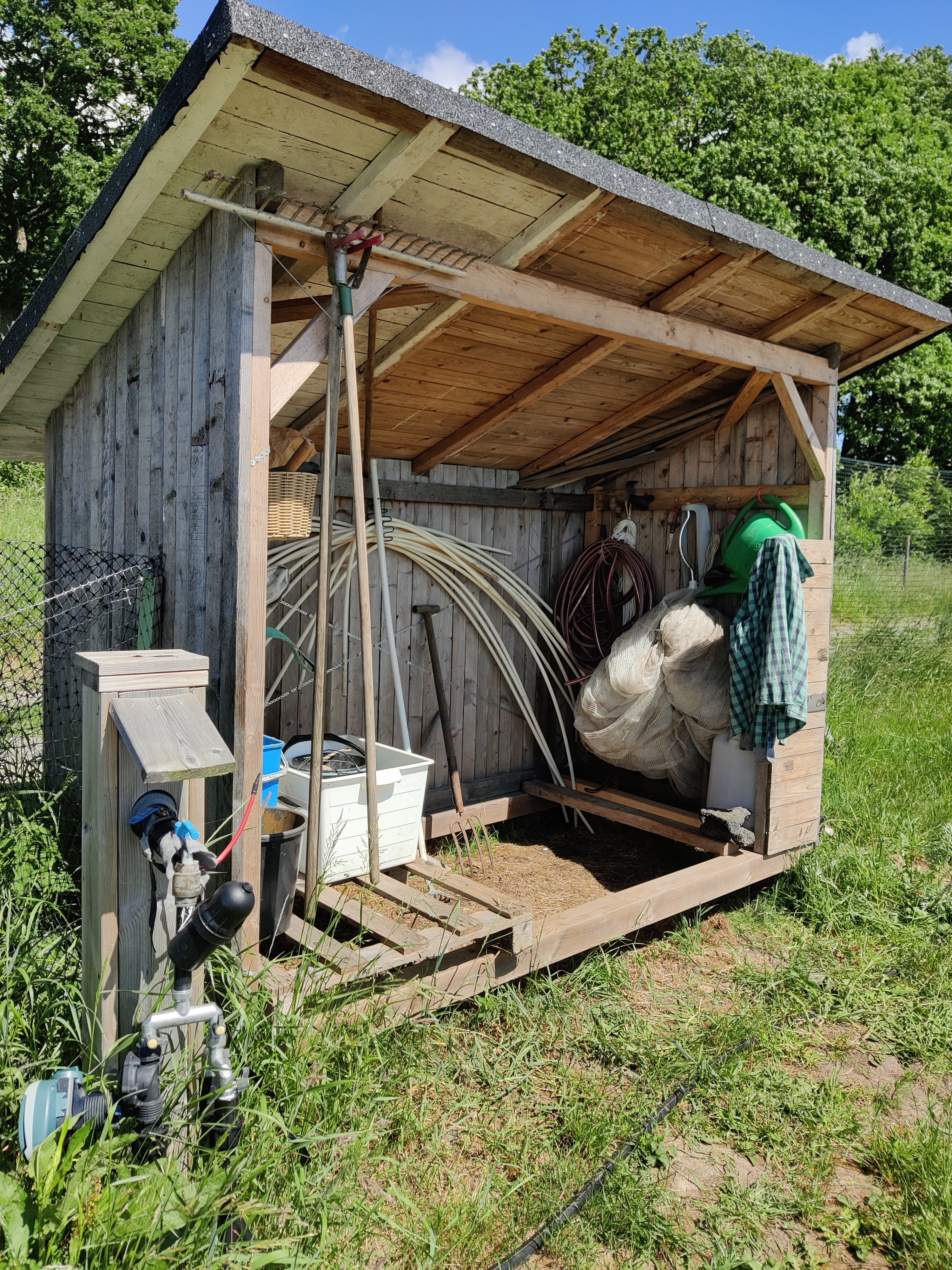 Förråd med tre väggar och snedtag, med olika verktyg. 